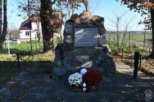 Obelisk w Pludwinach udekorowany kwiatami i zniczami