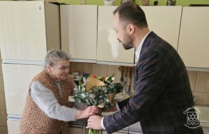 Złote Gody. Burmistrz Piotr Ślęzak wręcza bukiet kwiatów Grażynie Kowalskiej.