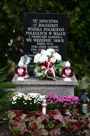 Mogiła żołnierska udekorowana kwiatami i zniczami