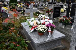 Mogiła żołnierska udekorowana kwiatami i zniczami