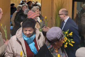 Burmistrz Strykowa wręcza tulipany paniom wychodzącym z sali DK