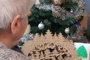 Seniorka spoglądająca na kartkę z życzeniami