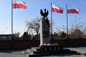 Pomnikiem Niepodległości w Strykowie, flagi narodowe, wiązanki kwiatów i znicze