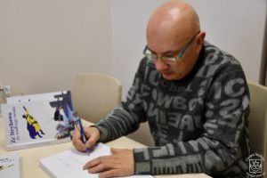 Jacek Perzyński podpisuje swoją nową książkę wydaną przez Gminę Stryków.