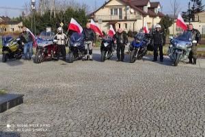 Strykowska Grupa Motocyklowa z narodowymi flagami przy Pomniku Niepodległości w Strykowie