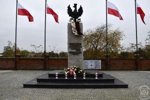 Pomnik Niepodległości w Strykowie udekorowany kwiatami i zniczami