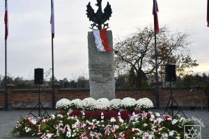 Pomnik Niepodległości w Strykowie, flagi narodowe, kwiaty, wiązanki kwiatów i znicze