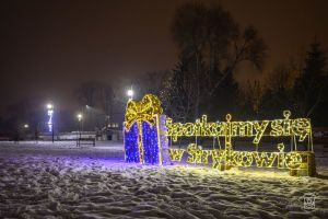 Iluminacje świąteczne w Strykowie: napis "Spotkajmy się w Strykowie oraz dekoracje świetlne na lampach - park nad Moszczenicą